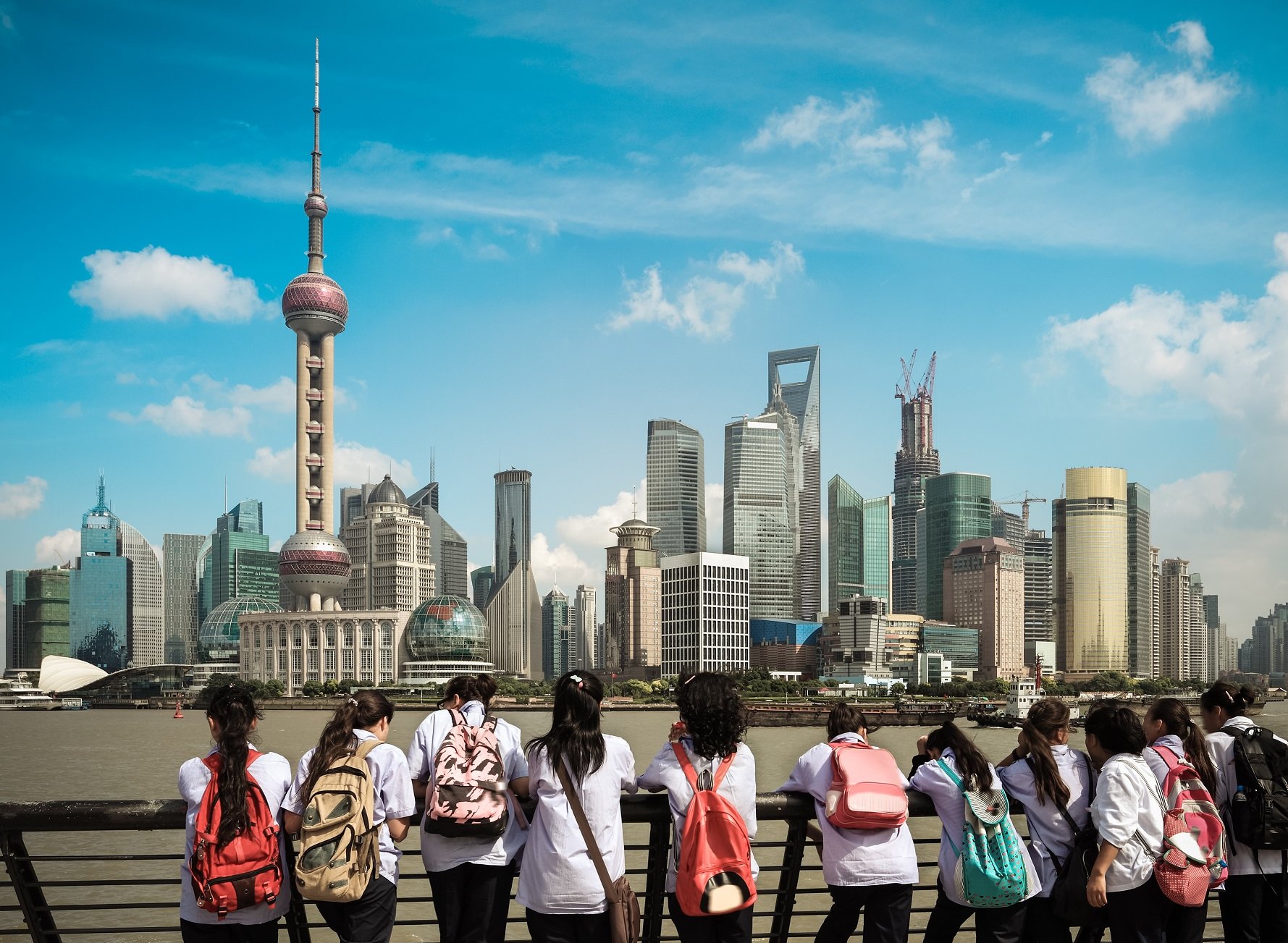Students looking across the river at the Shanghai skyline, China